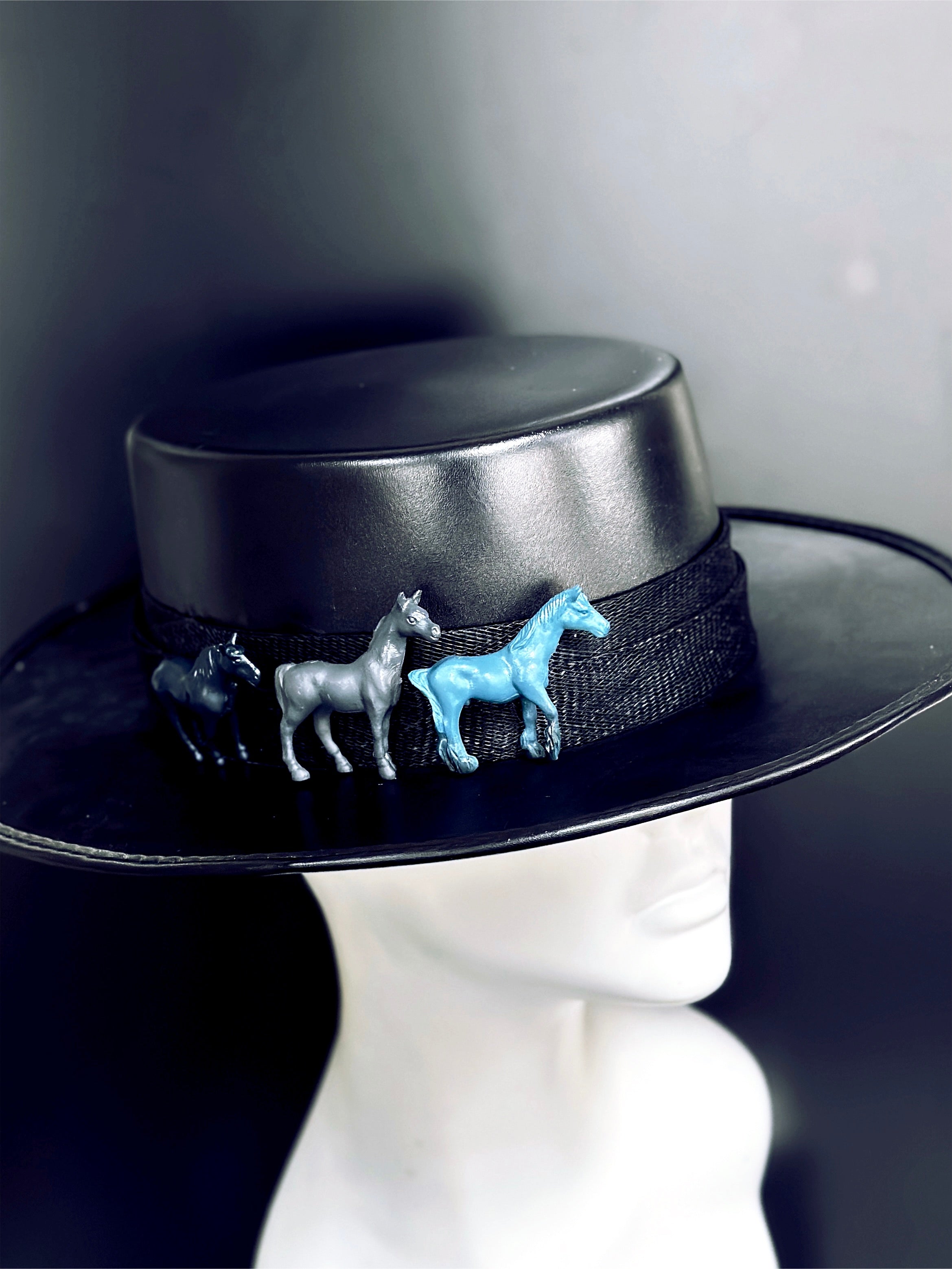 Black wide-brim hat with three horses in blue, gray, and black.