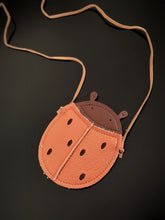 Kids ladybug-shaped mini crossbody bag with tan strap and stitched faux leather in orange and brown.