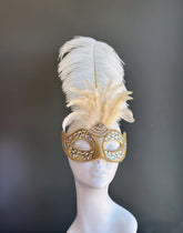 Gold masquerade mask with crystal embellishments and ivory feathers for Venetian ball and gala occasions.