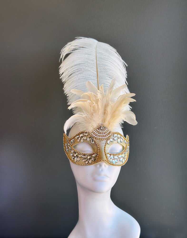 Gold masquerade mask with crystal embellishments and ivory feathers for Venetian ball and gala occasions.
