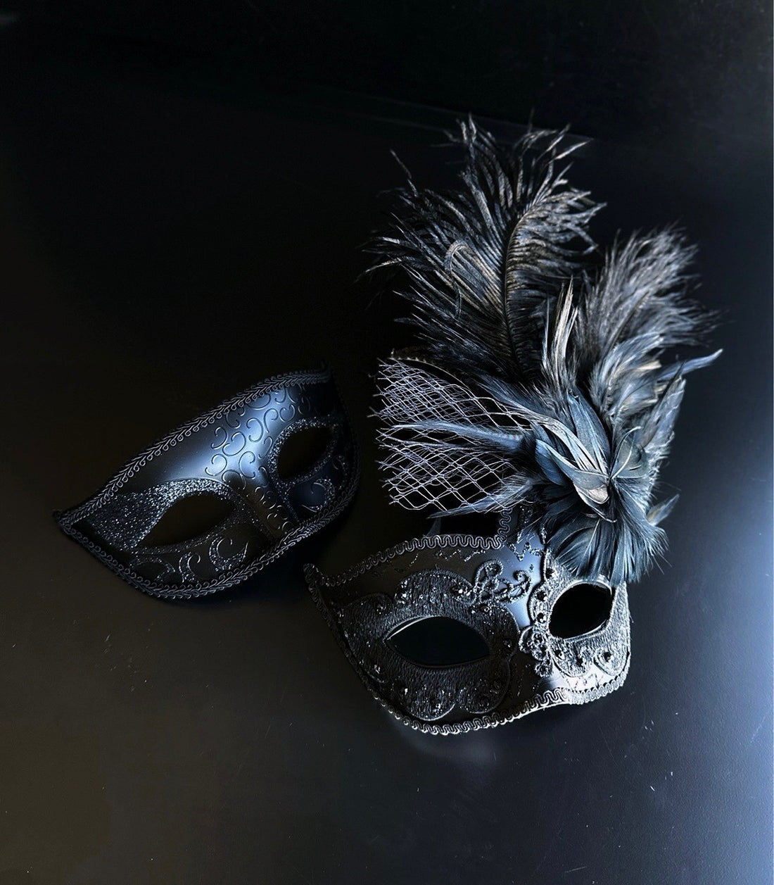 Black feather masquerade mask set with plume and embossed detailing for formal events.