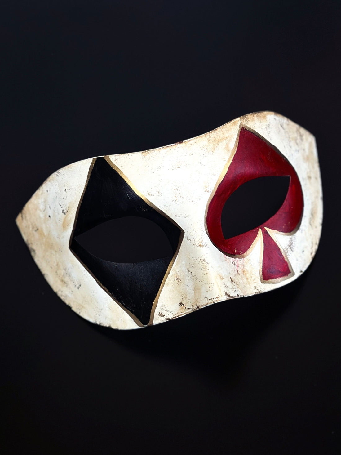 Diamond and spade card symbols in black and red over the eyes on a masquerade mask.
