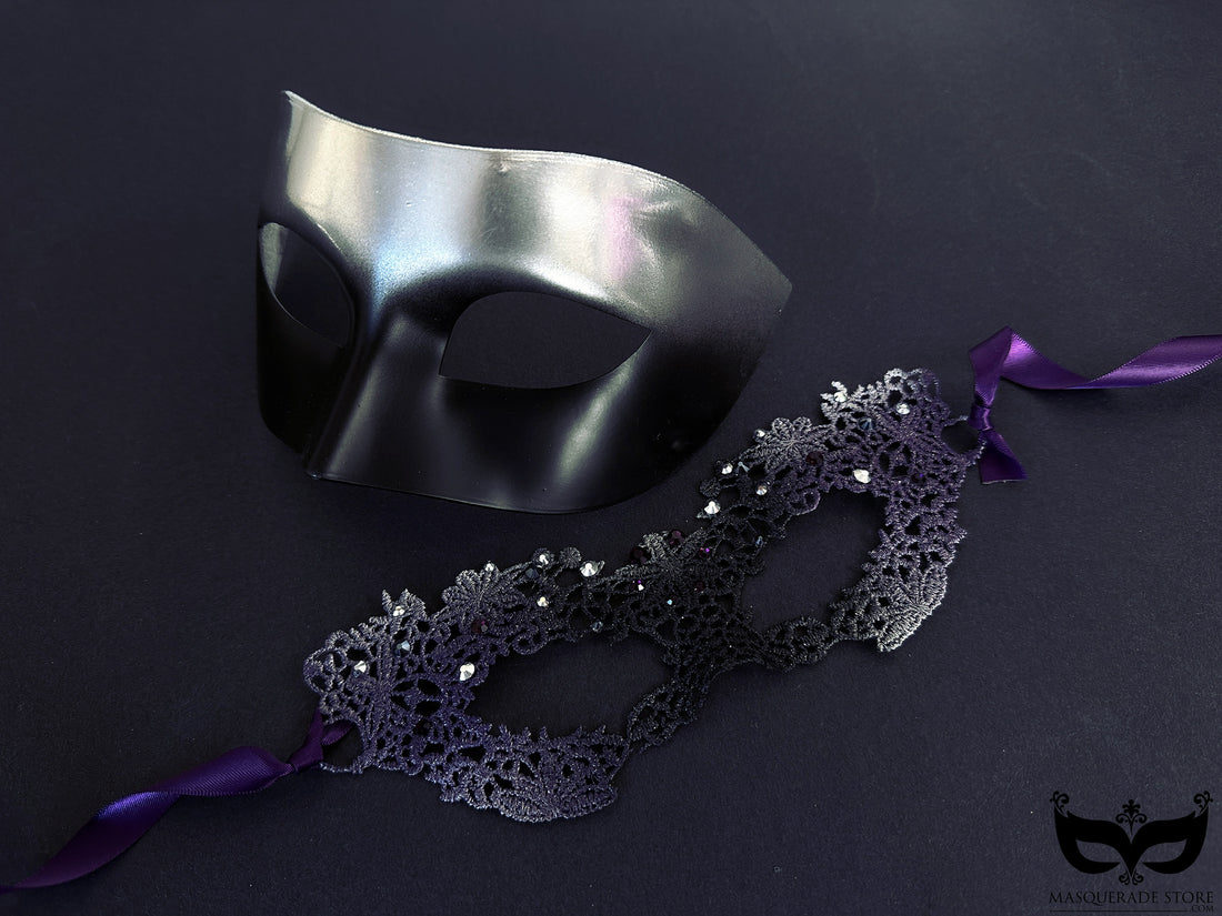 A sleek black men’s mask paired with an intricate black and silver lace women’s mask, perfect for masquerade balls and romantic events.