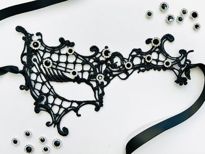 Black embroidered spiderweb lace masquerade mask with sparkling black rhinestones and satin ribbon ties. Perfect for Halloween, gothic costumes, masquerade balls, vampire cosplay, Venetian masquerade events, Mardi Gras celebrations, theatrical performances, gothic weddings, fantasy costumes, and elegant evening wear.
