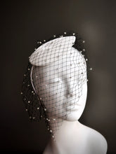White fascinator hat with black rhinestone veil.

