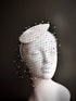 White fascinator hat with black rhinestone veil.

