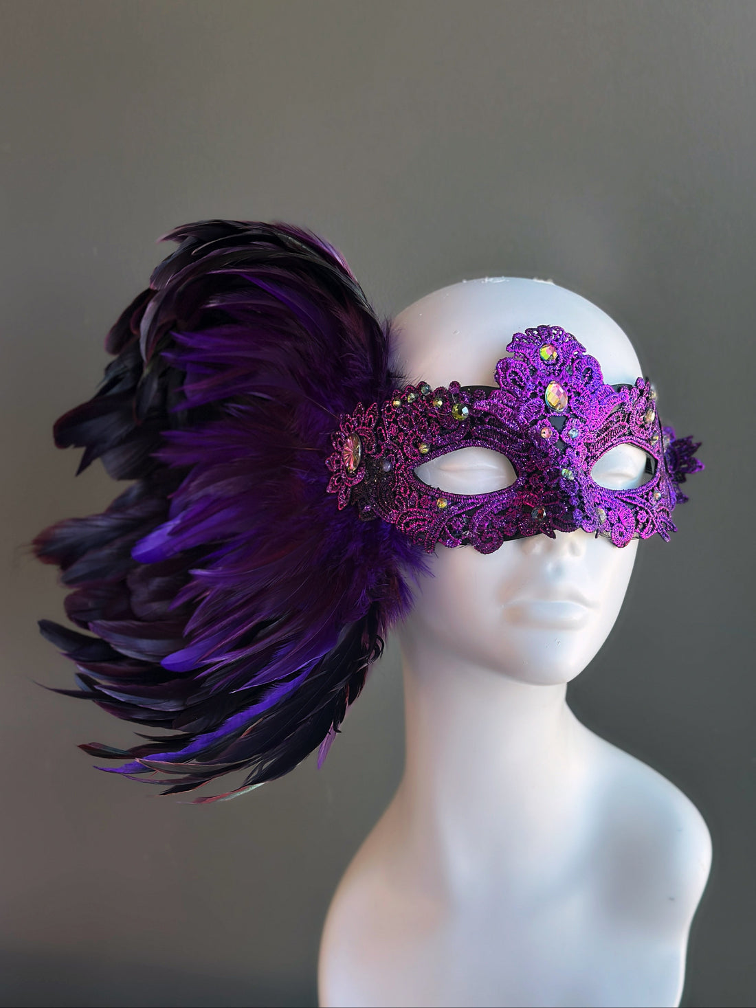 Purple and black feather masquerade mask with intricate lace and rhinestone embellishments.
