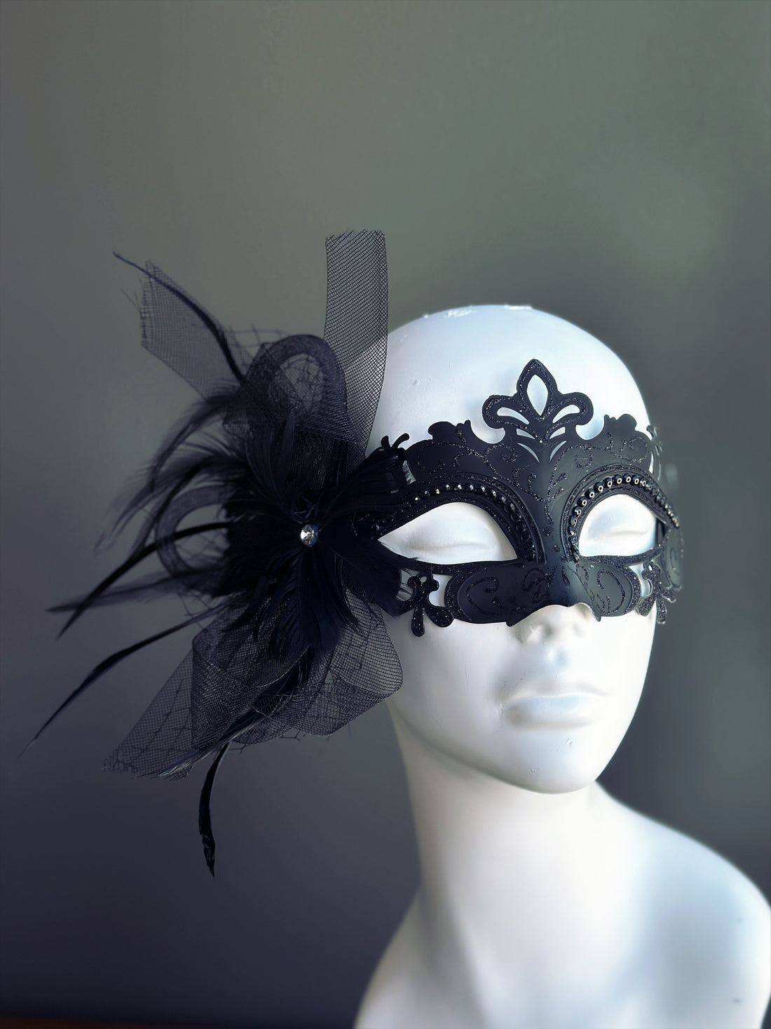 Black metal masquerade mask with black feathers, mesh, and rhinestones