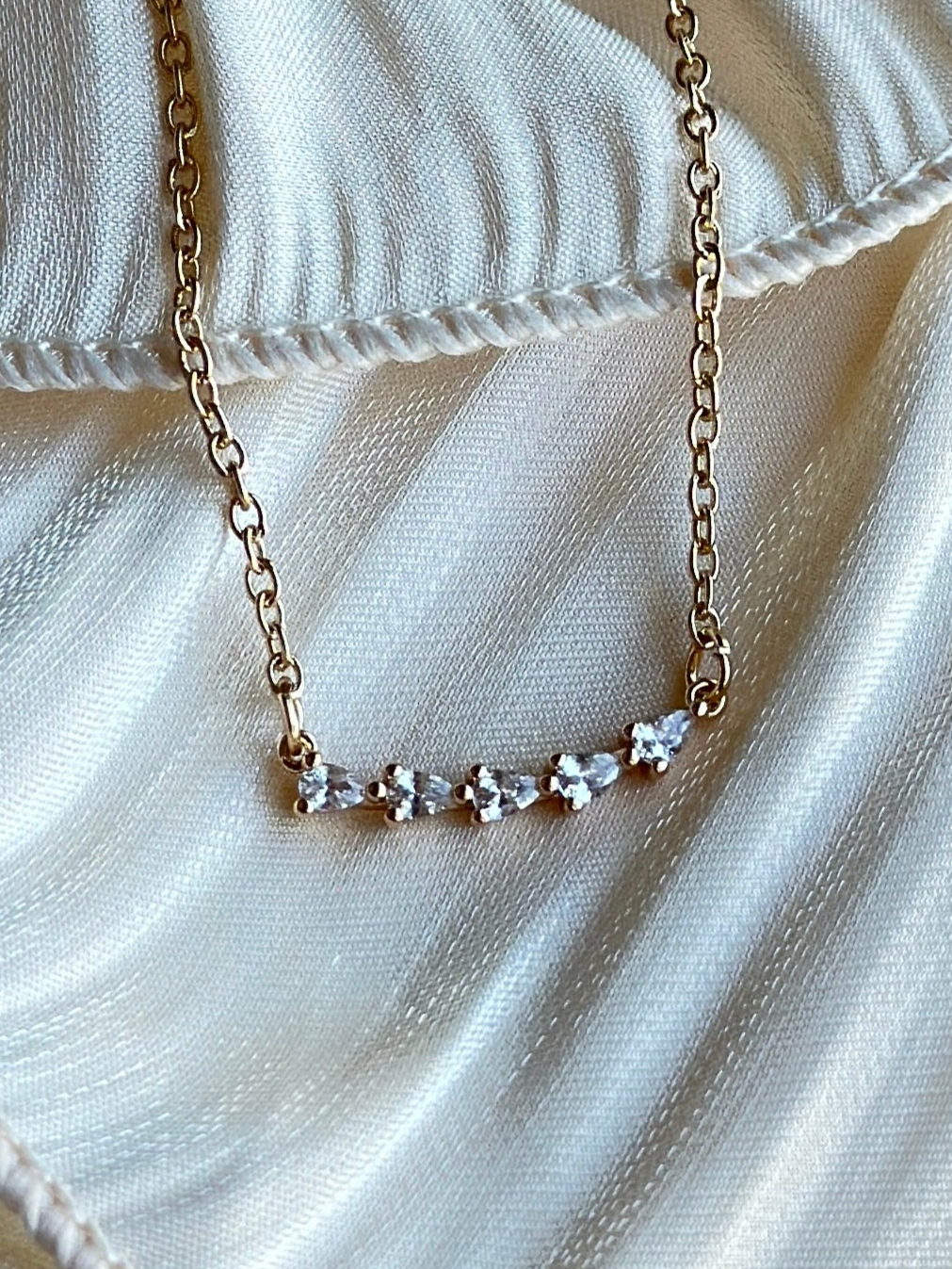 Gold plated necklace featuring clear stones.