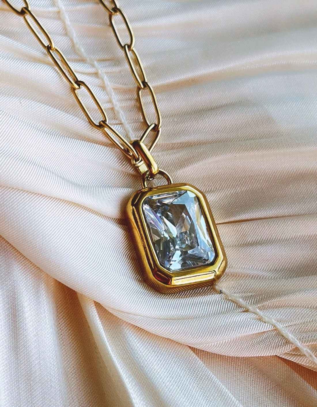 Gold chain with a large clear gemstone pendant.