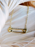 Gold plated necklace with a gold safety pin pendant adorned with clear crystals.
