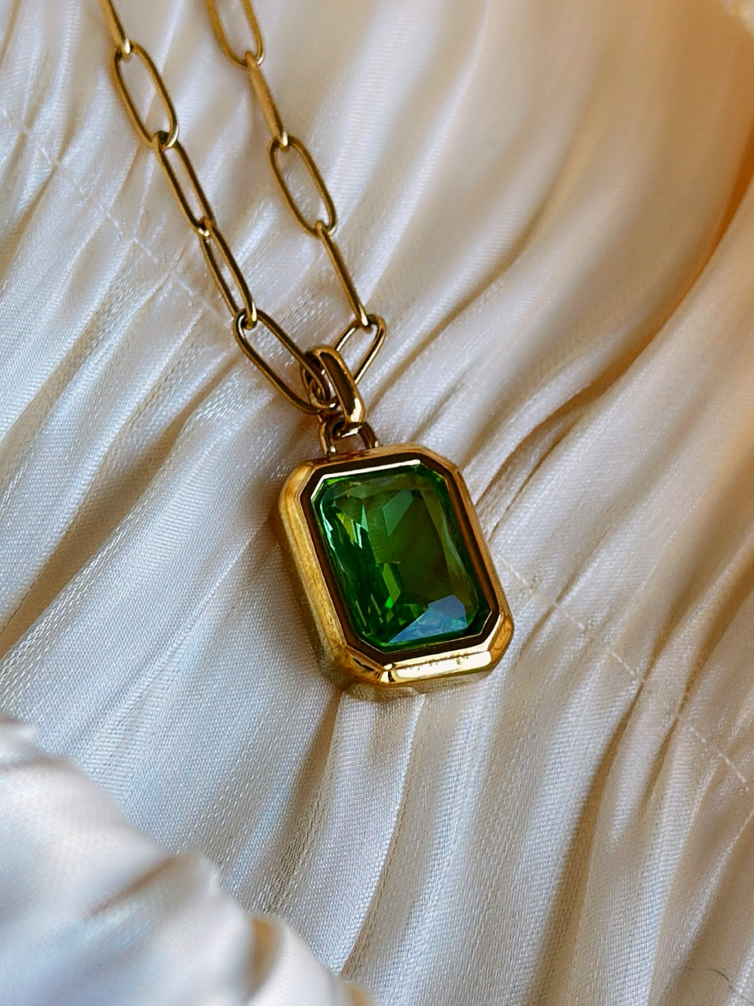 Gold necklace with a green gemstone pendant.