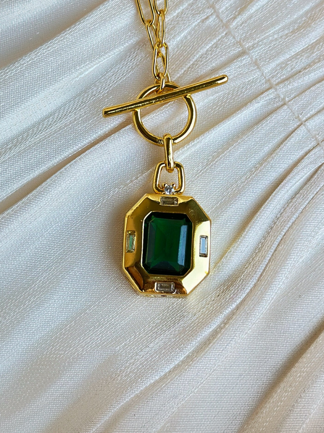 Gold necklace with a green gemstone pendant.