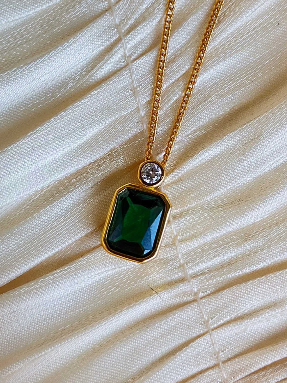 Gold necklace with a green gemstone pendant.