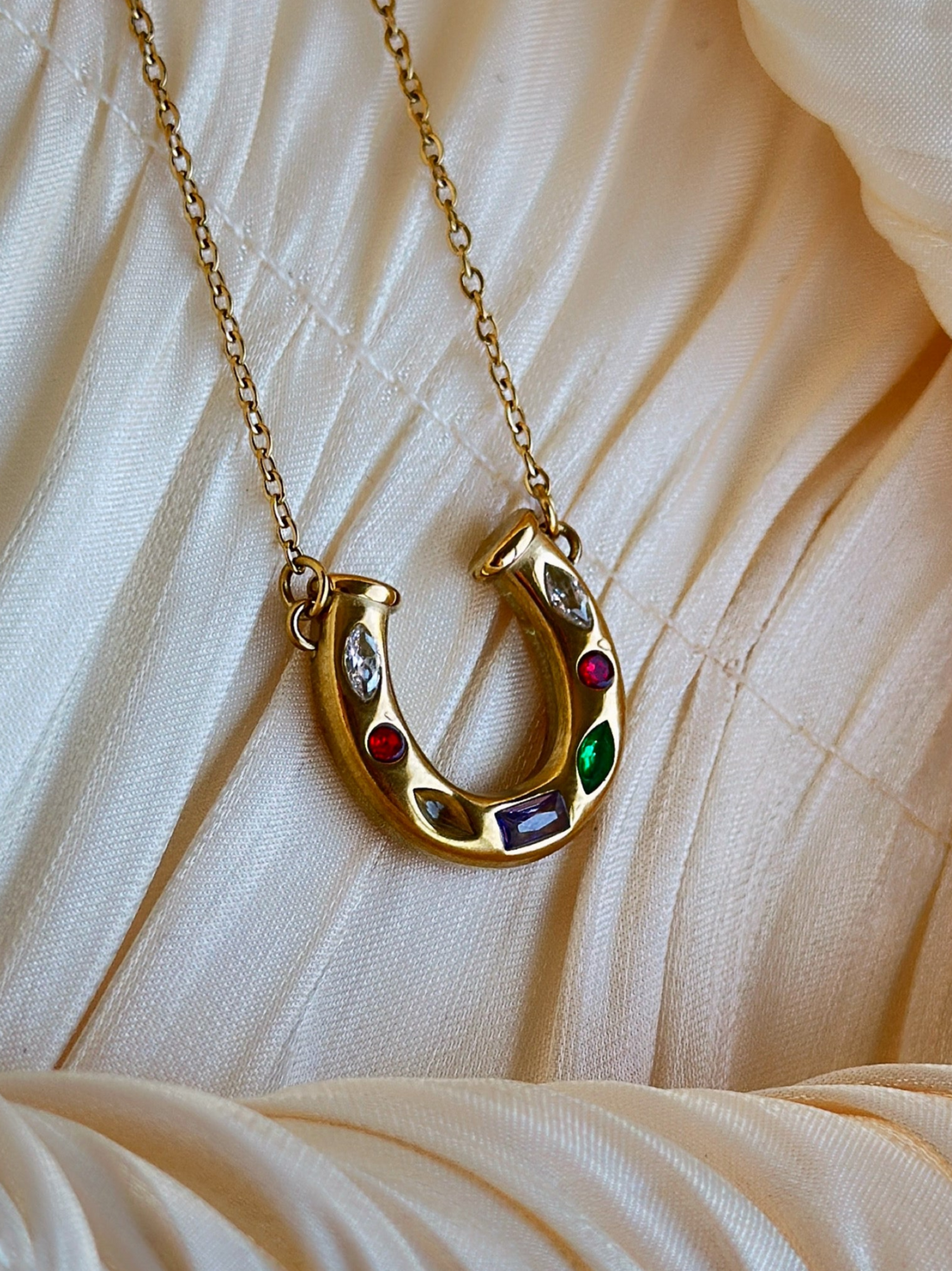 Gold horseshoe necklace with colored gemstones.
