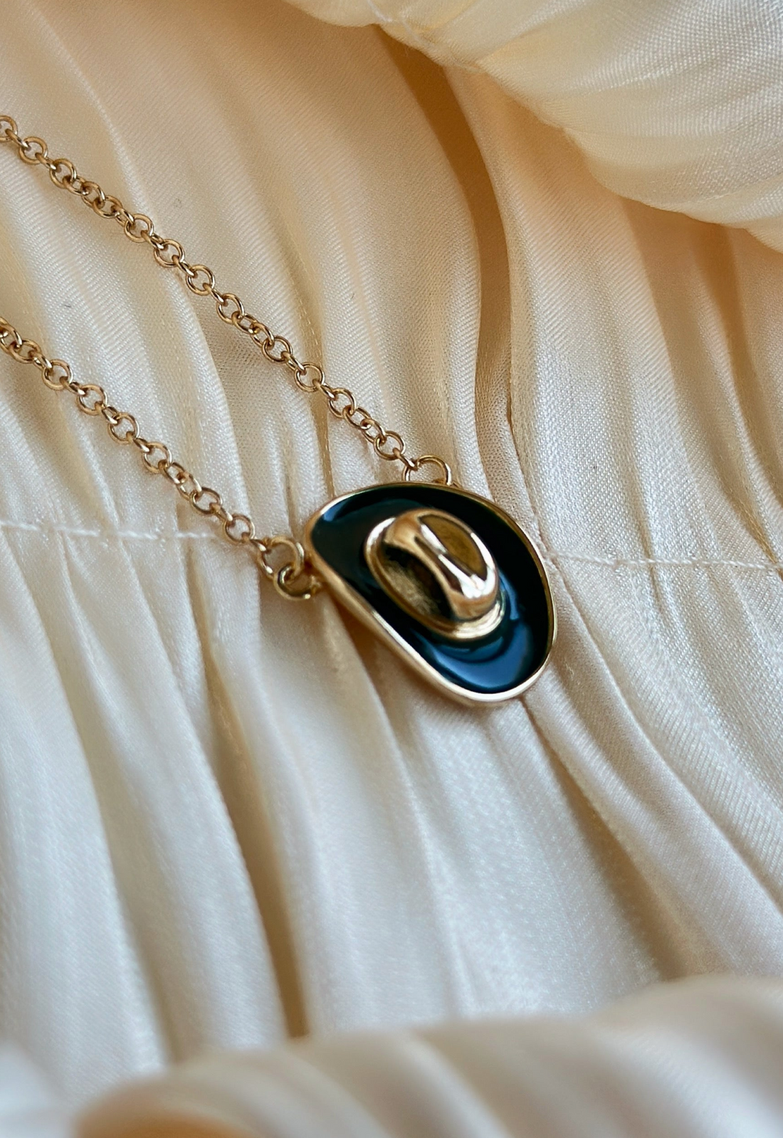 Necklace with a gold and green 
pendant on a beige fabric background