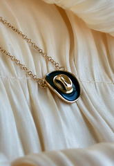 Necklace with a gold and green 
pendant on a beige fabric background