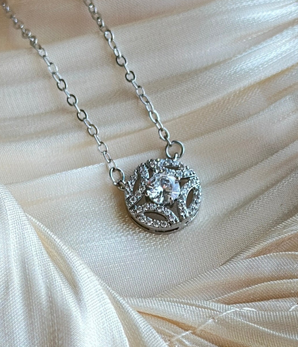 Silver necklace with a round pendant covered in dazzling clear crystals surrounding a larger center stone.