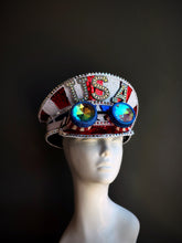 Patriotic sequin captain hat with red, white, and blue embellishments, rhinestones, and oversized reflective goggles for a bold festival look.