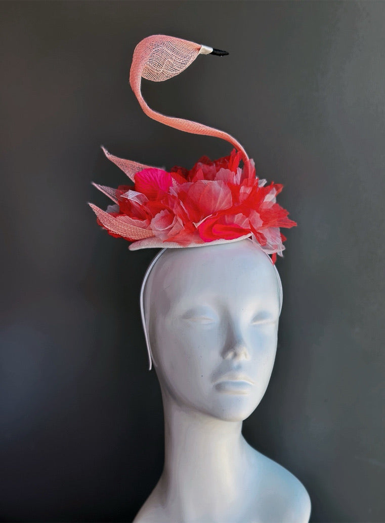 Pink flamingo fascinator headpiece with sculptural curved neck silhouette and layered floral embellishments on lightweight millinery base
