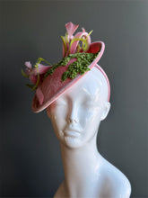 Pink velvet fascinator hat with green floral applique and feathers.