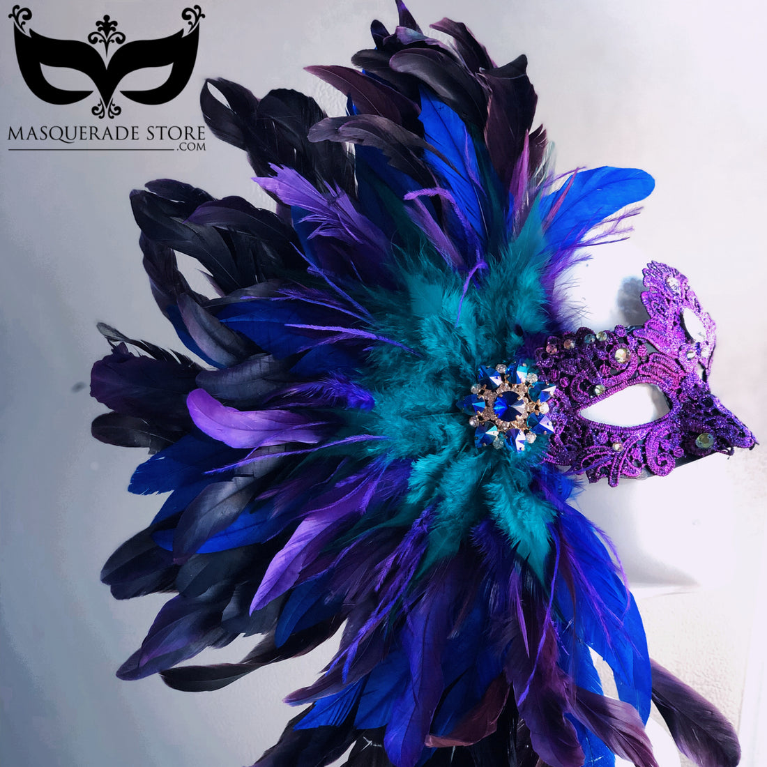 Purple and teal masquerade mask with jeweled rhinestone accent and dramatic feather plume.