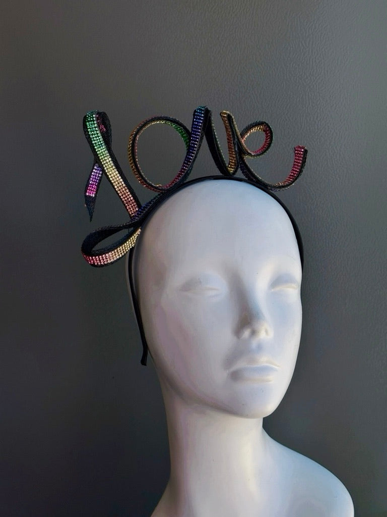 Rainbow rhinestone LOVE headband with multicolor crystal lettering on a black metal headband, perfect for Pride Month, LGBTQ+ celebrations, rainbow festivals, Pride parade outfits, drag shows, music festivals, equality marches, queer events, and colorful statement fashion.