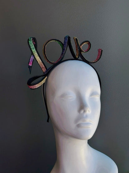 Rainbow rhinestone LOVE headband with multicolor crystal lettering on a black metal headband, perfect for Pride Month, LGBTQ+ celebrations, rainbow festivals, Pride parade outfits, drag shows, music festivals, equality marches, queer events, and colorful statement fashion.