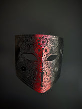 Laser-cut metal mask with an ombre gradient from deep crimson red in the center to black edges, featuring intricate filigree detailing.

