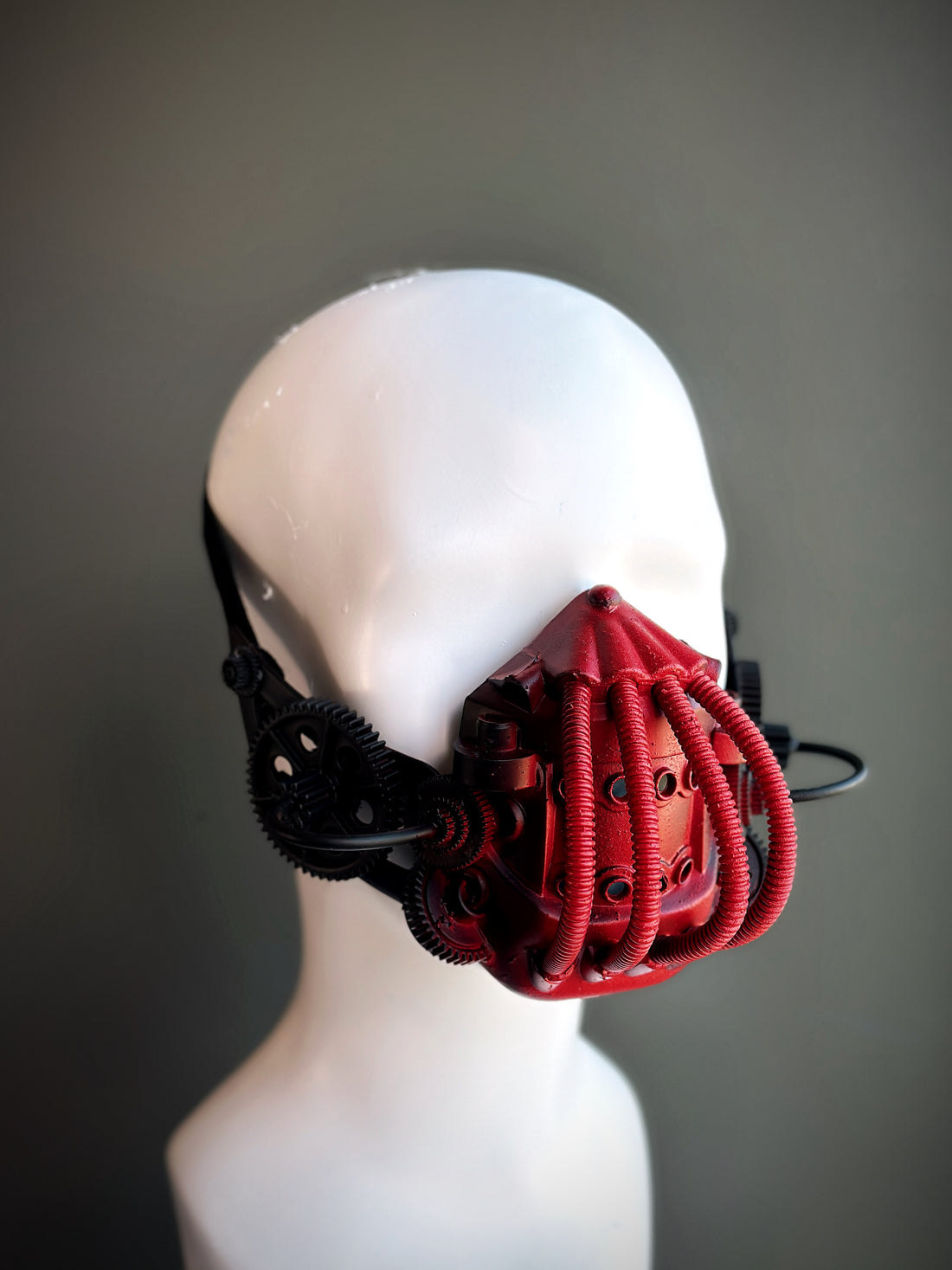 Red and black steampunk respirator mask with gears, tubing, and mechanical details, perfect for cosplay, gothic, and cyberpunk fashion.

