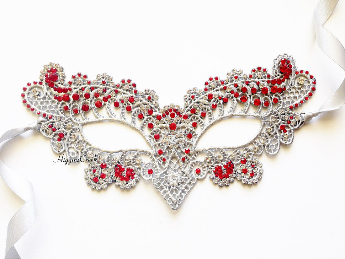 Silver lace masquerade mask adorned with red rhinestones and ribbon ties