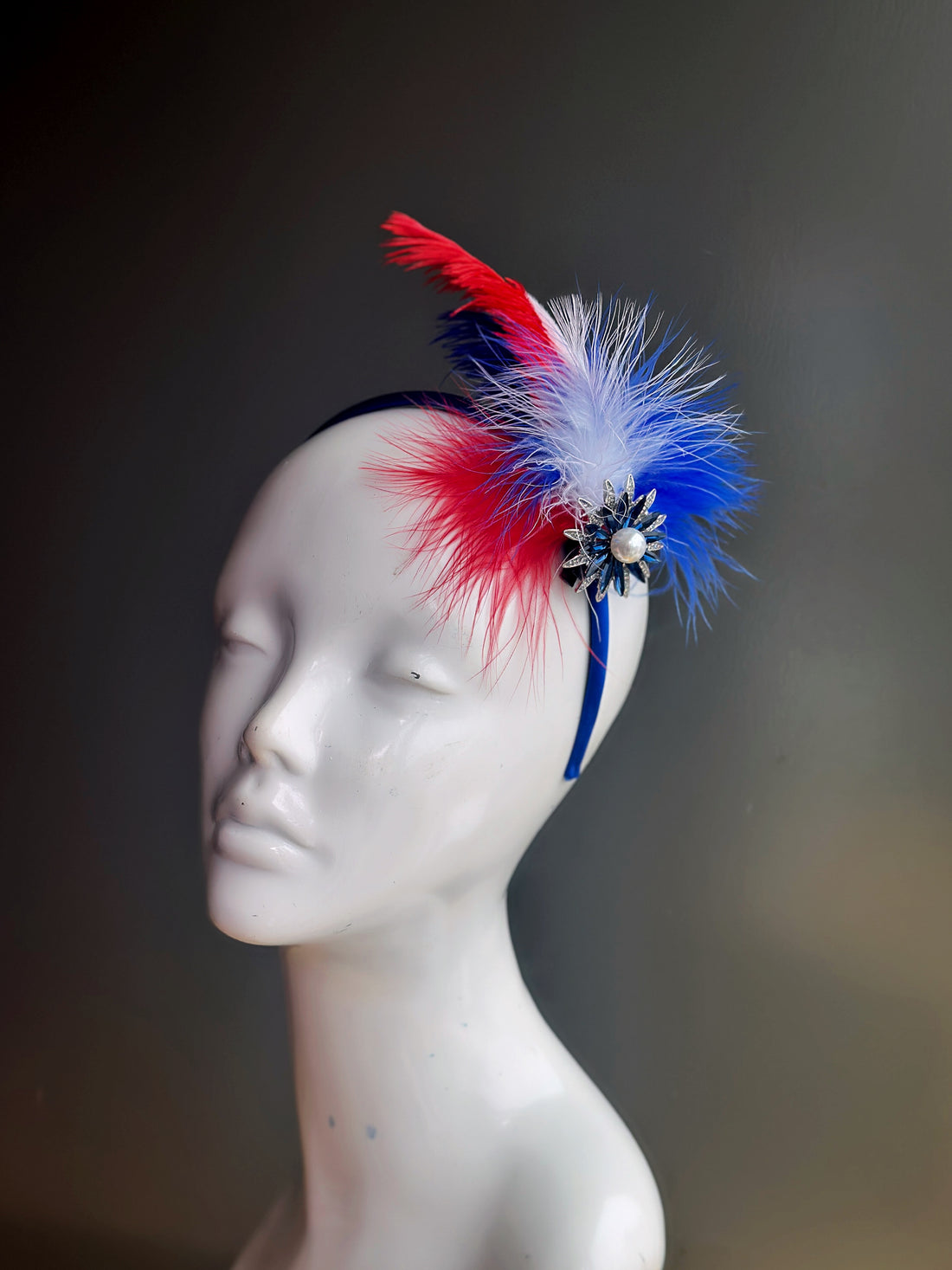 Red, white, and blue feather fascinator with starburst brooch, ideal for patriotic celebrations and festive events.