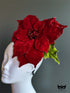 Red poinsettia holiday fascinator hat with layered velvet petals on mannequin