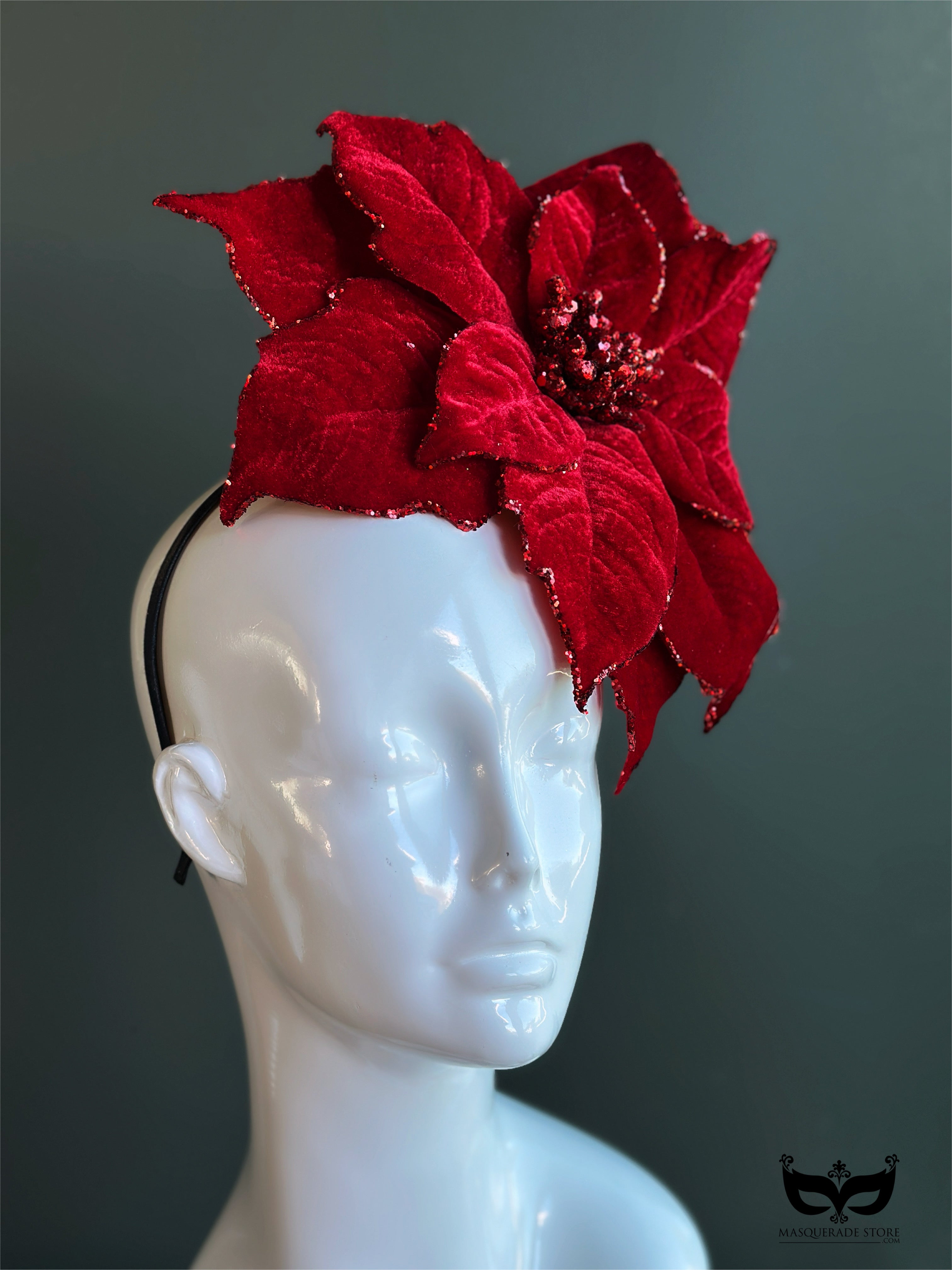 Red poinsettia holiday fascinator hat with layered velvet petals on mannequin