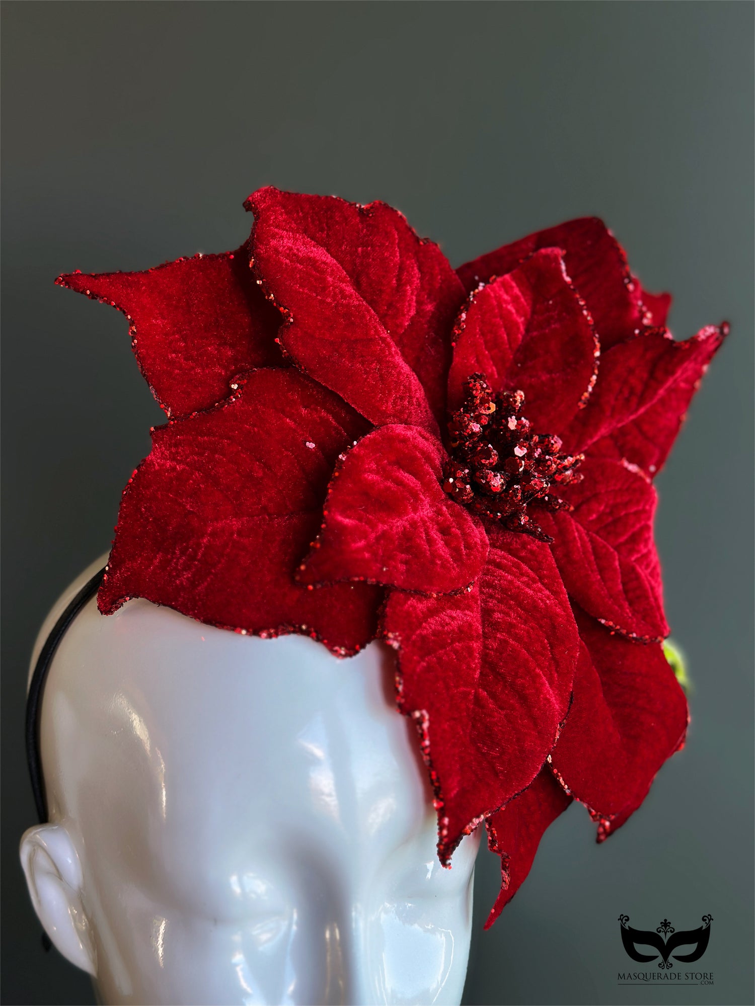 Red poinsettia holiday fascinator hat with layered velvet petals on mannequin