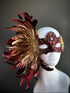 Red and gold feather masquerade mask with opulent plume design and ornate lace accents.