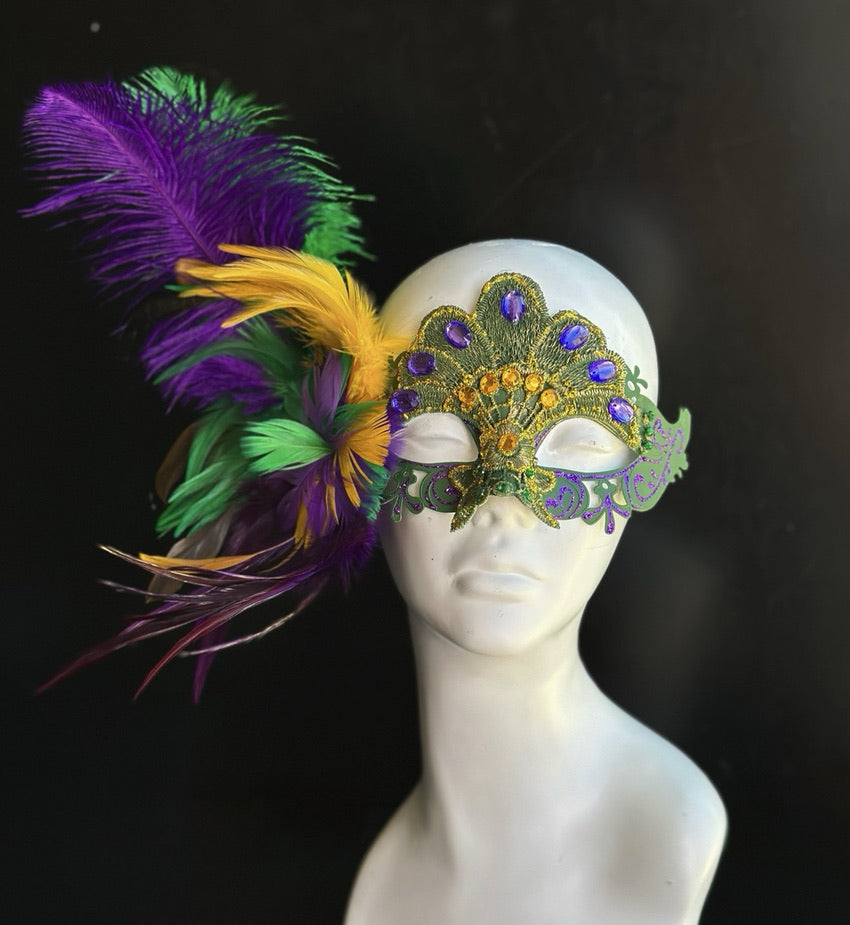 Purple, green, and gold Mardi Gras masquerade mask featuring embroidered lace, sparkling acrylic rhinestones, shimmering sequins, and dramatic faux peacock-inspired feathers. Ideal for Carnival festivals, Mardi Gras celebrations, Venetian masquerade balls, Halloween parties, cosplay conventions, theatrical performances, ballroom galas, costume events, and elegant formal occasions.