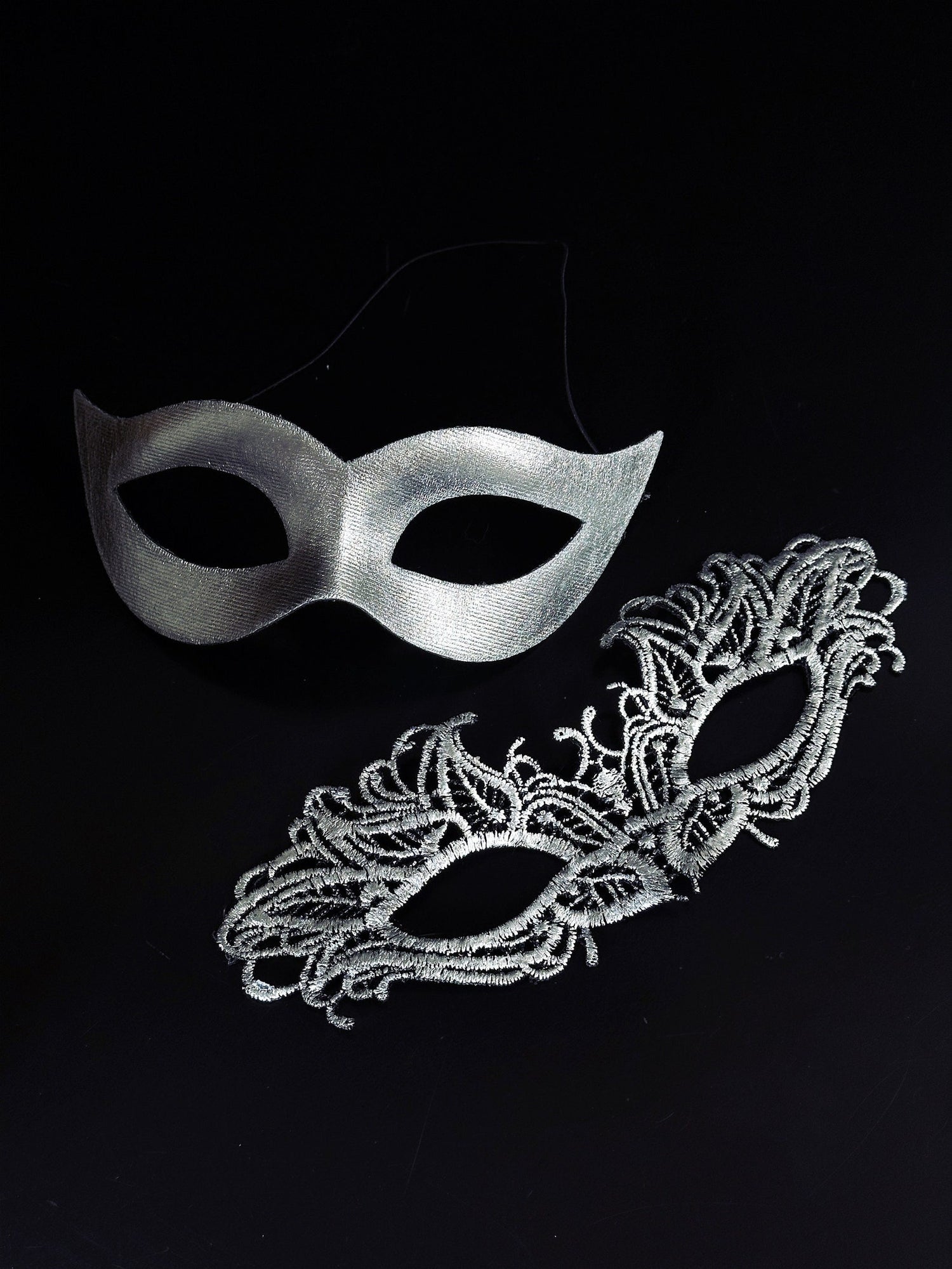 Elegant silver couples masquerade masks featuring a sleek cat-eye men’s mask and a delicate lace women’s mask, perfect for Venetian balls, weddings, and themed celebrations.