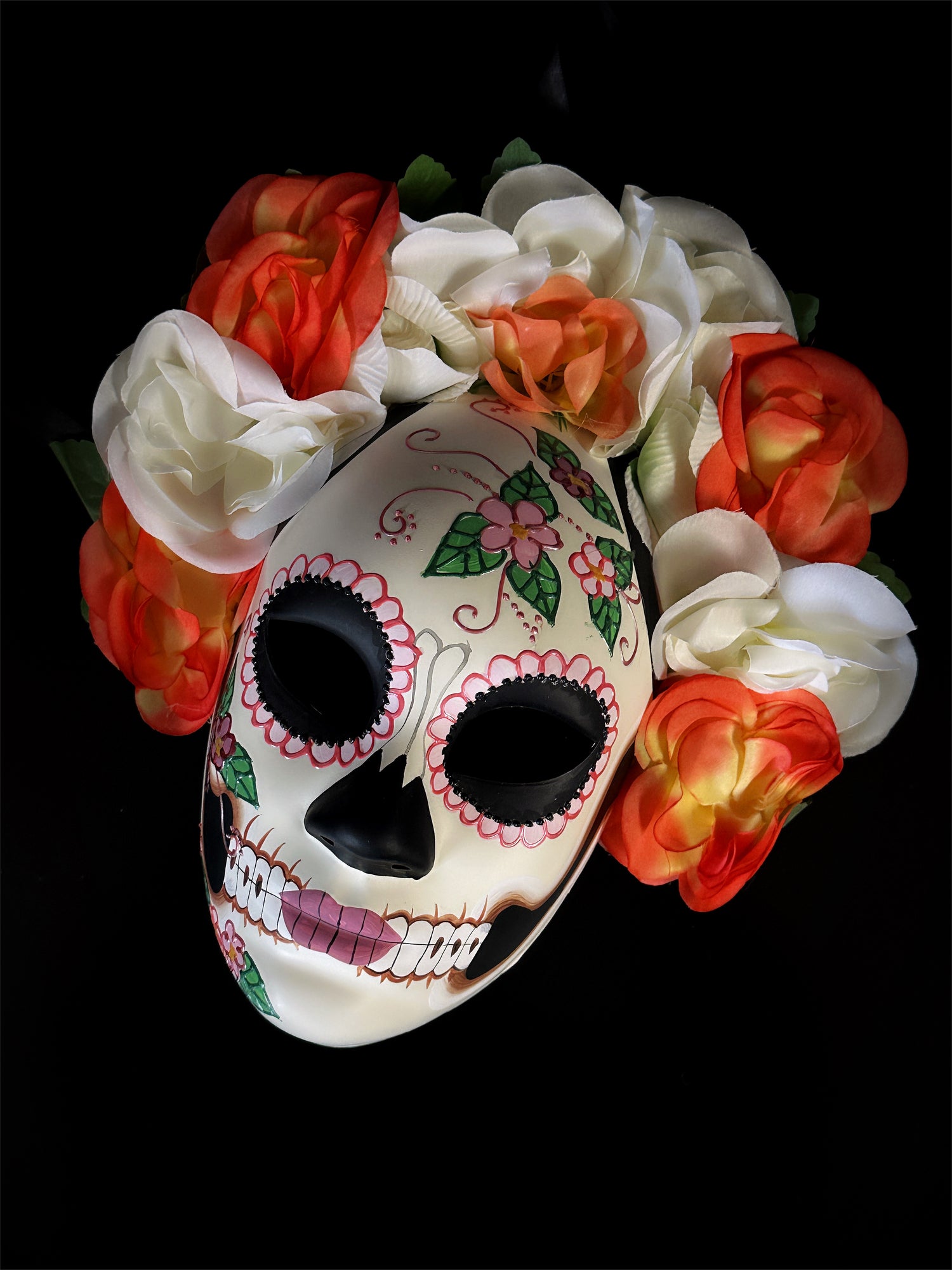 Sugar skull mask with red, orange, and white floral accents, perfect for Dia de los Muertos celebrations

