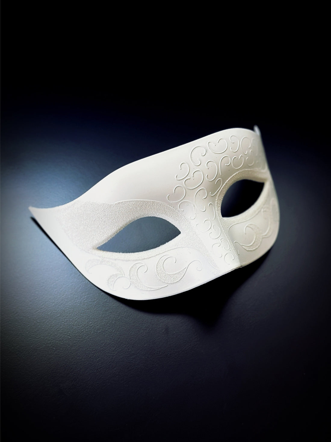 White Venetian mask with embossed swirl details, perfect for masquerade balls, weddings, and elegant events.

