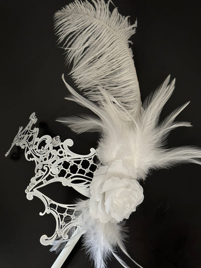 White metal handheld masquerade mask with feathers, rhinestones, and a flower on a stick.