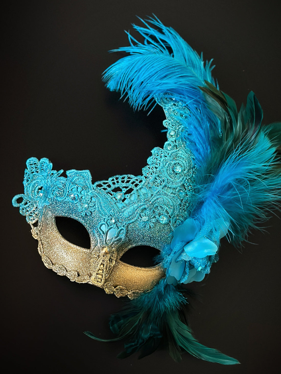 Turquoise gold mask set with feathers and gems.