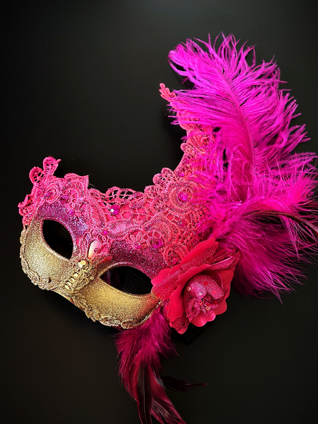 Hot pink and gold mask with feathers and gems.