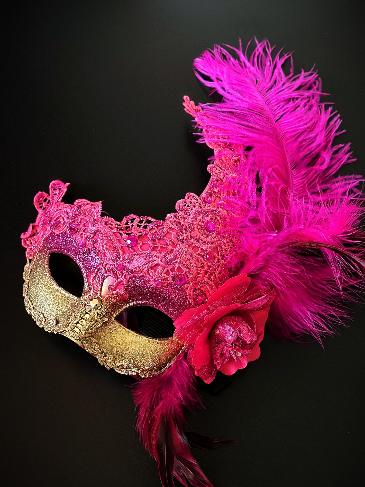 Hot pink and gold mask with feathers and gems.
