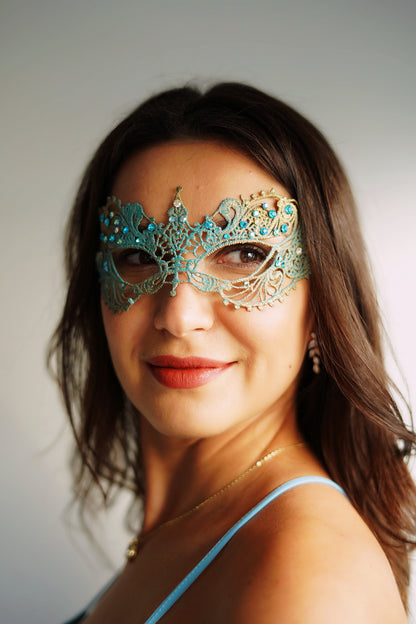 Lace masquerade mask in turquoise and gold with turquoise and iridescent rhinestones.
