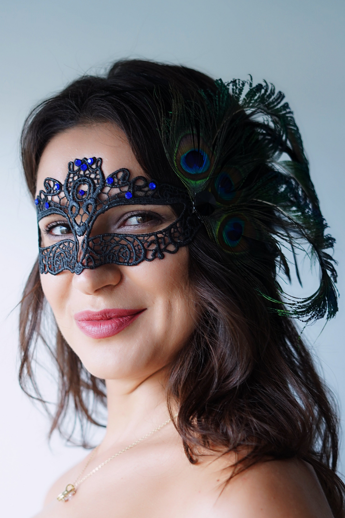 Black lace masquerade mask with sapphire blue rhinestones and peacock feathers.