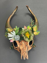 Fantasy woodland ram skull headdress featuring sculpted curved ram horns, faux flowers, moss, berries, and forest greenery. Ideal for Halloween, fantasy cosplay, Renaissance fairs, LARP, pagan festivals, woodland weddings, theatrical performances, fairy festivals, medieval events, and nature-inspired costume photography.
