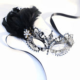 Elegant black feathered masquerade mask made of filigree-cut metal and adorned with rhinestones.